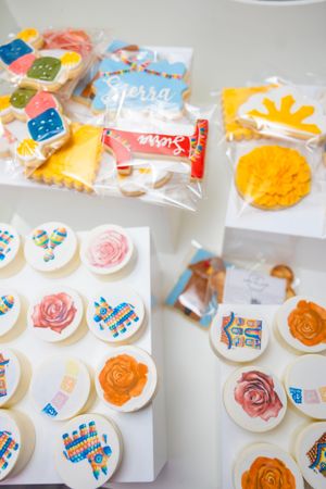 Assorted decorated sugar cookies with floral and fiesta designs displayed in packaging.
