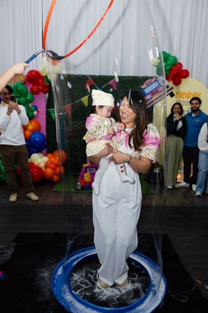 Mother holding baby inside giant soap bubble at Sierra's fiesta-themed first birthday party celebration.