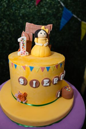 Yellow fondant first birthday cake with Filipino Barbie doll topper and name Sierra for 1st Fiesta party.