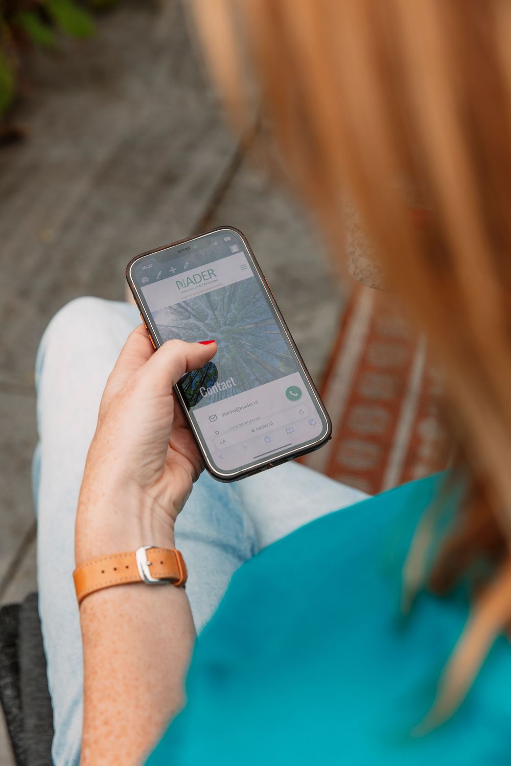 Hand holding smartphone while relaxing on outdoor furniture.