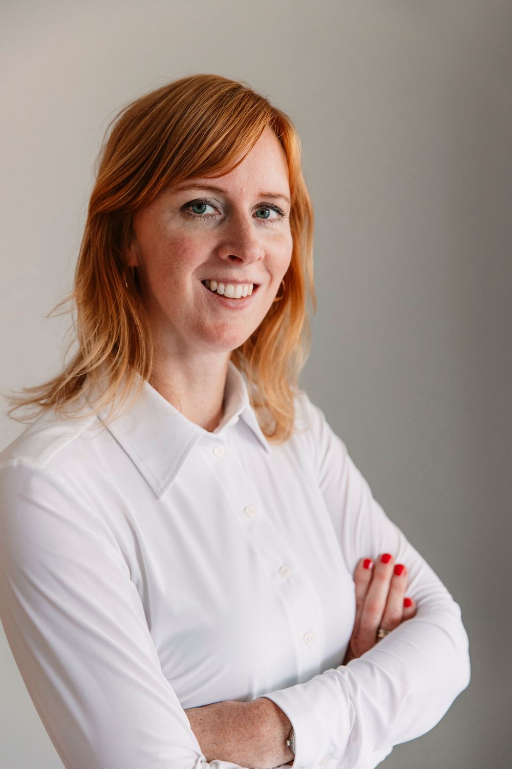 Person in white button-up shirt posing against neutral background.