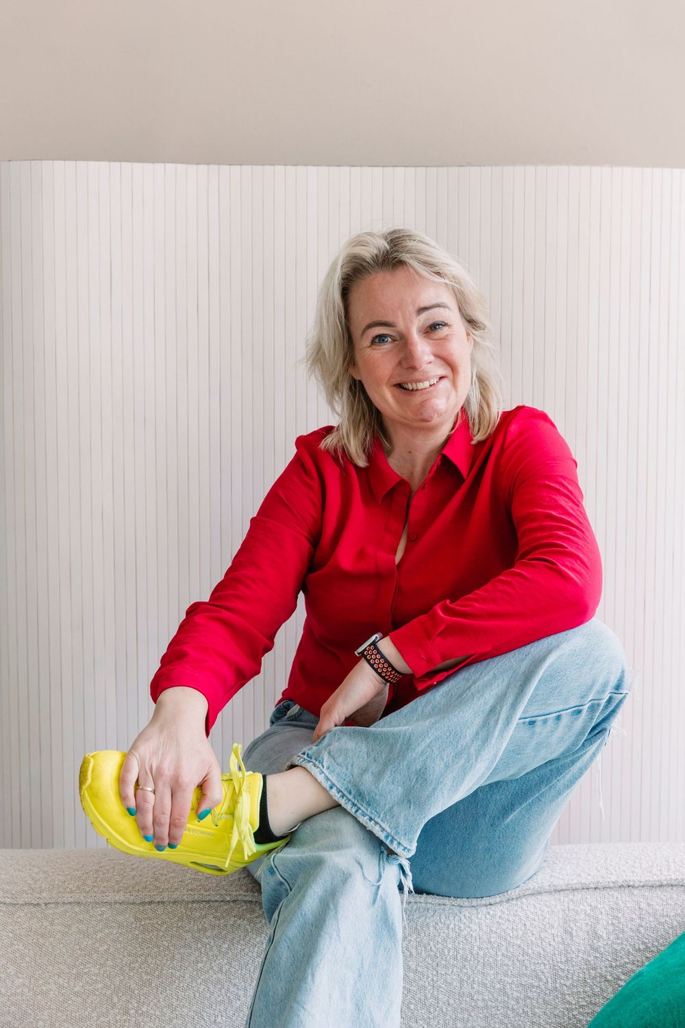 Person in red shirt and jeans relaxing on white couch with yellow cleaning gloves.