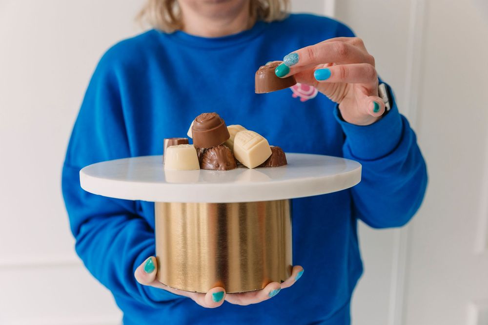 Hands holding dessert treats while wearing bright blue sweater.