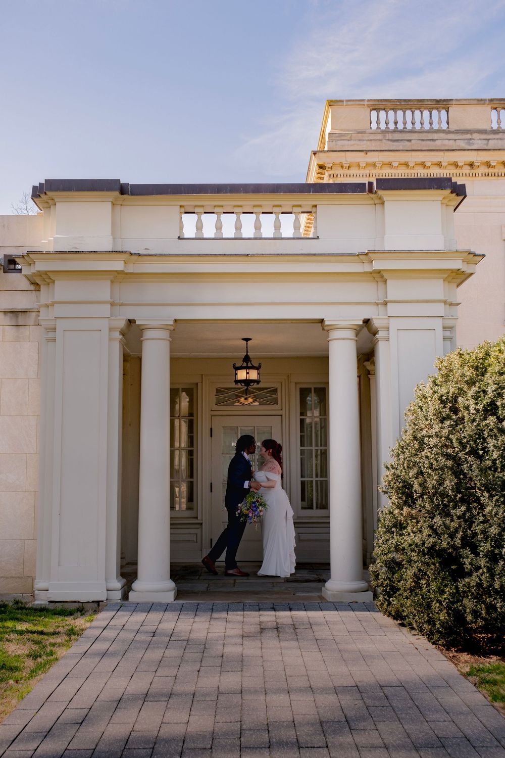 A series of elegant white columns and archways at a classic wedding venue during a ceremony.