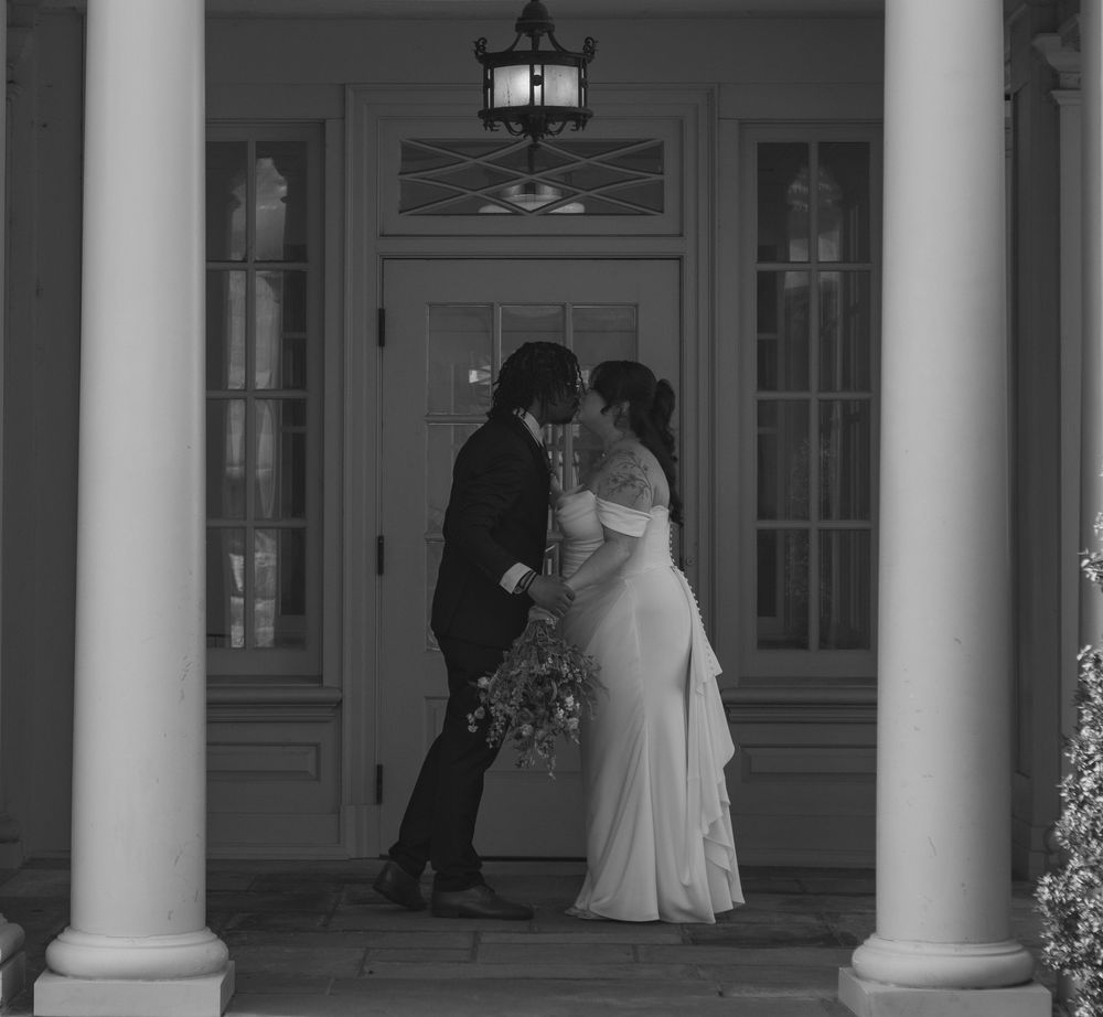 Black and white photo of a wedding ceremony taking place under classical white columns.