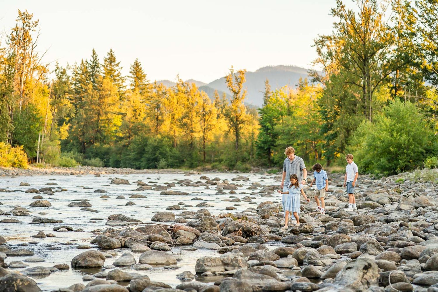 Kids walking on the rocks by the river.