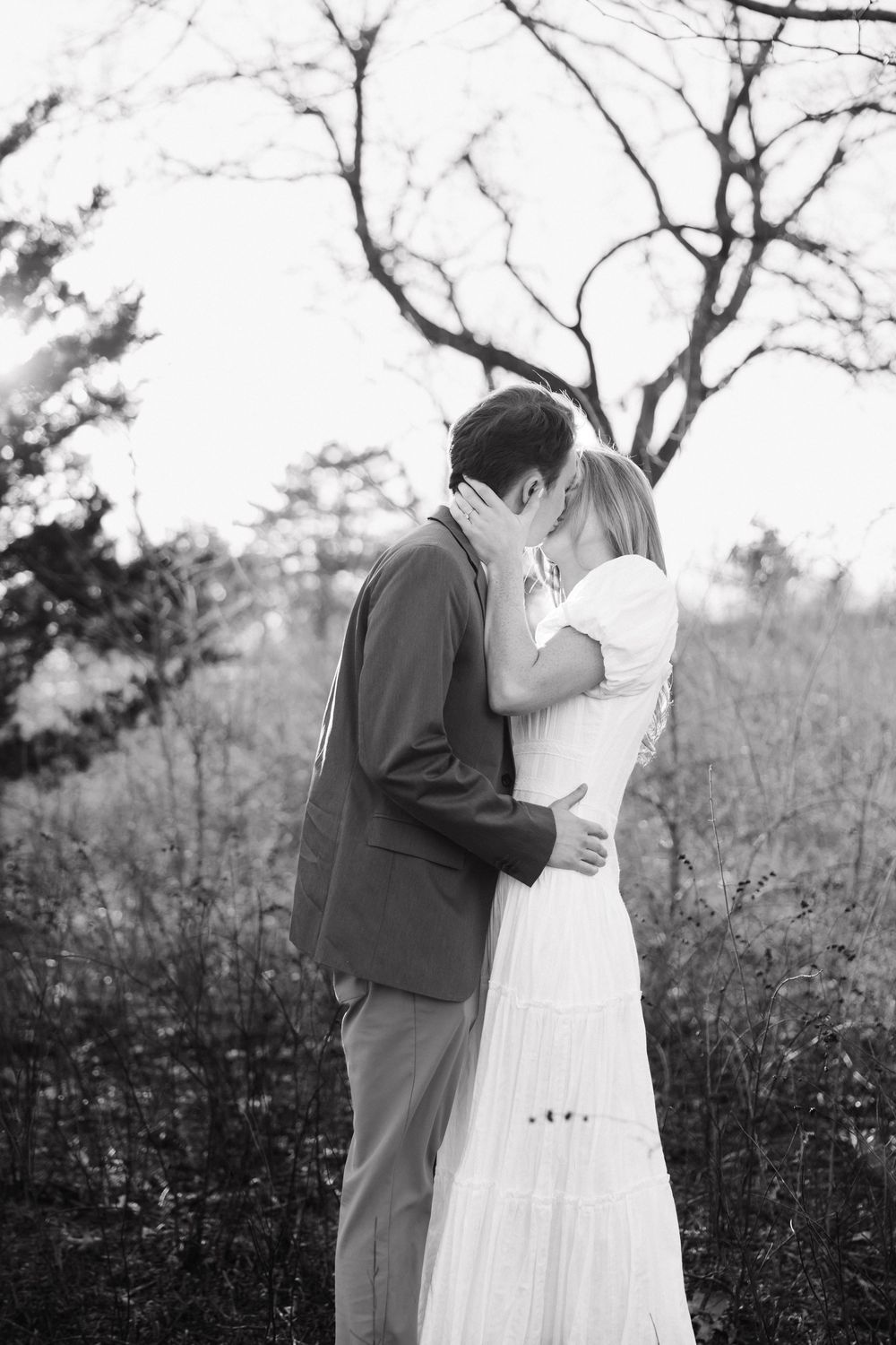Black and white romantic wedding photos show a couple embracing in a natural outdoor setting with bare trees.