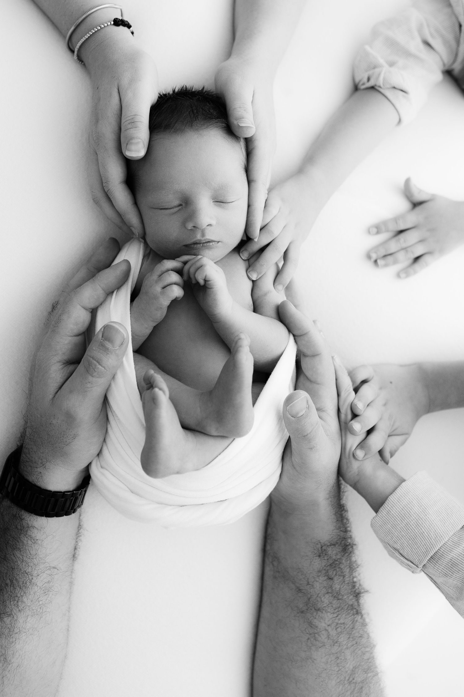 Black and white newborn photography series showing baby details and parent hands.