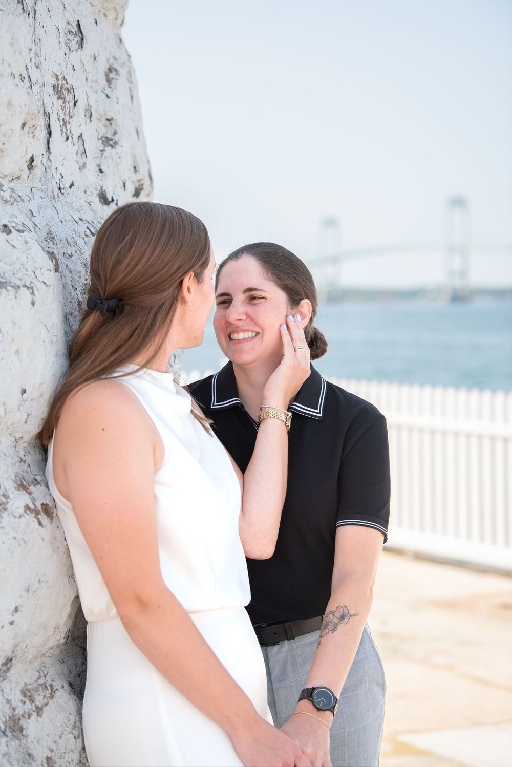 A romantic seaside photoshoot showing tender moments between a couple in white and black attire.
