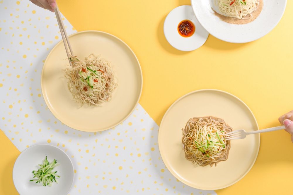 Overhead view of small white plates with various garnished dishes on a yellow polka dot background.
