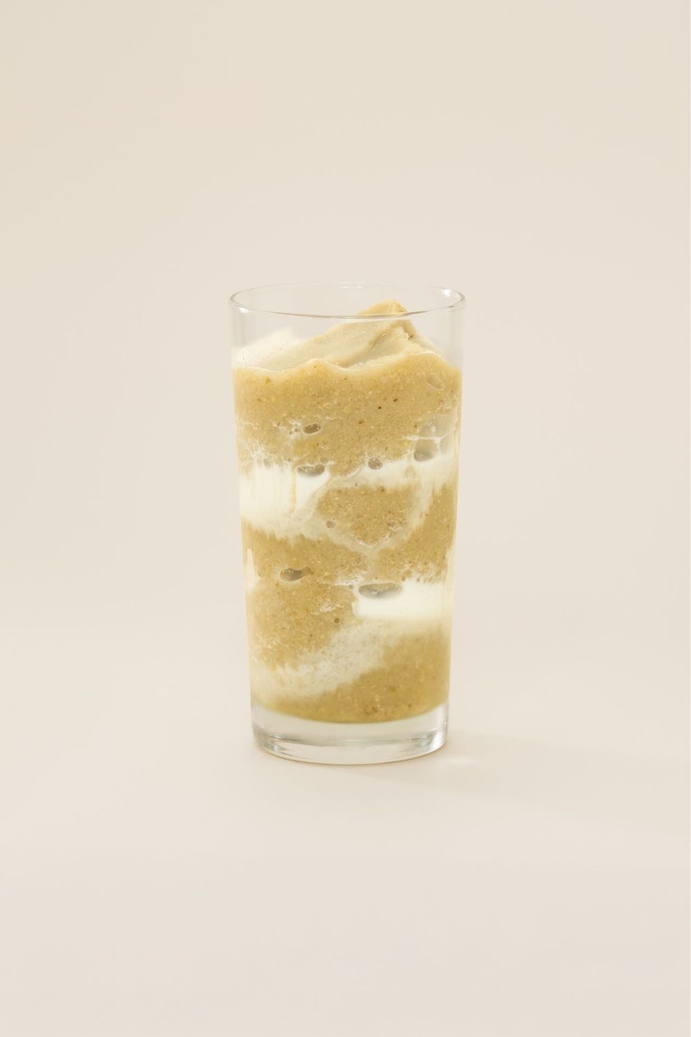 Three clear glass cups filled with creamy yellow smoothie or milkshake dessert.