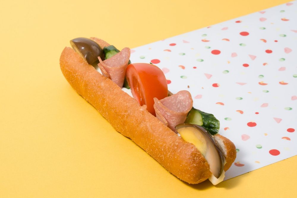 A hot dog with toppings being held in a polka dot wrapper is shown from multiple angles in a sequence.