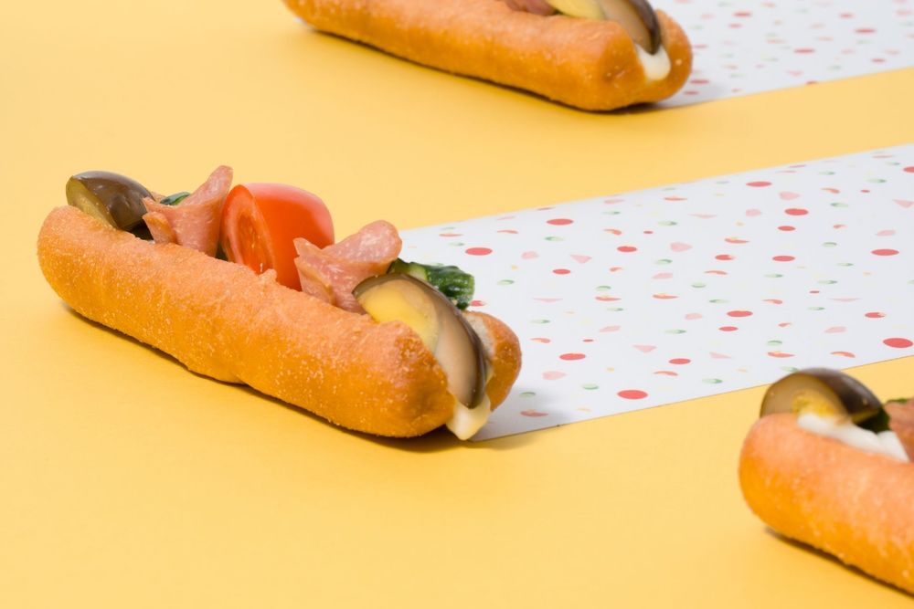 Multiple hot dogs arranged in a row on a yellow background with polka dot pattern paper.