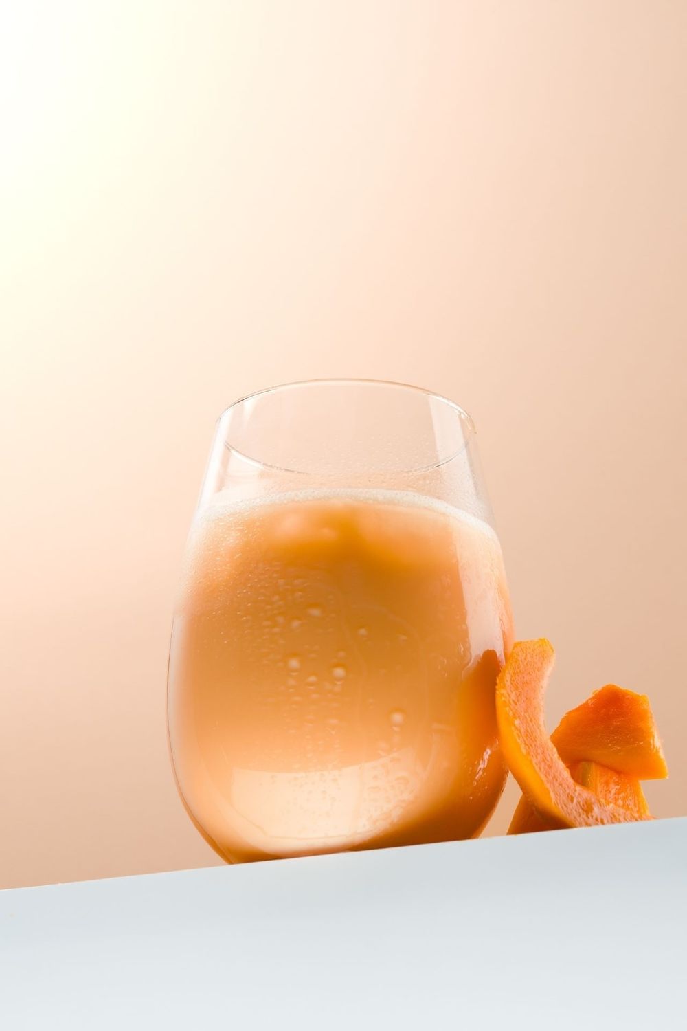 A glass of pink champagne or sparkling wine shown in a minimalist sequence against a light background.