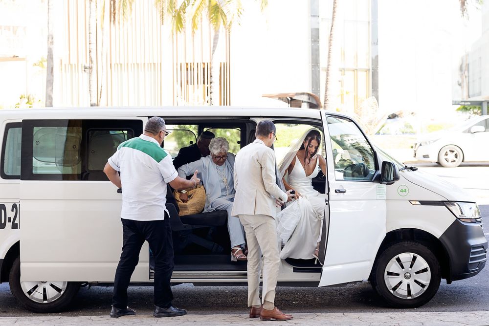 A row of white luxury cars parked outside with people gathering near them.
