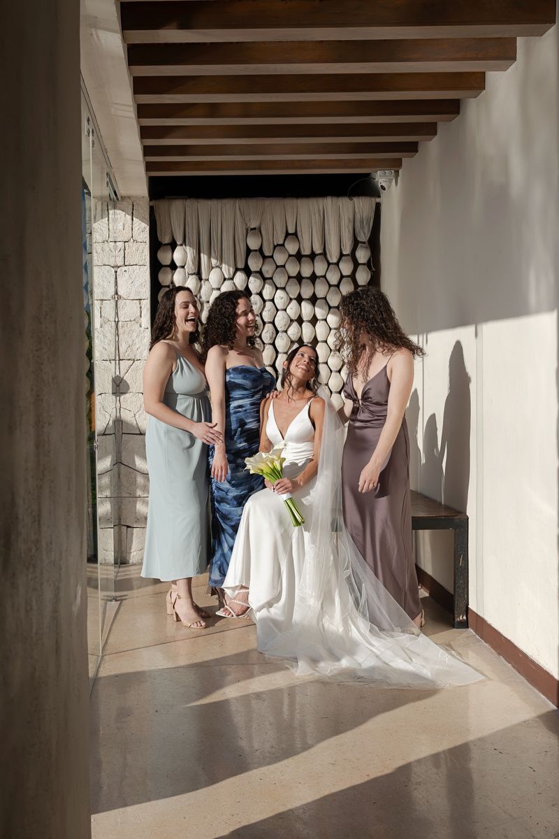 Wedding party gathered in a sunlit hallway with wooden beams and decorative wall features.