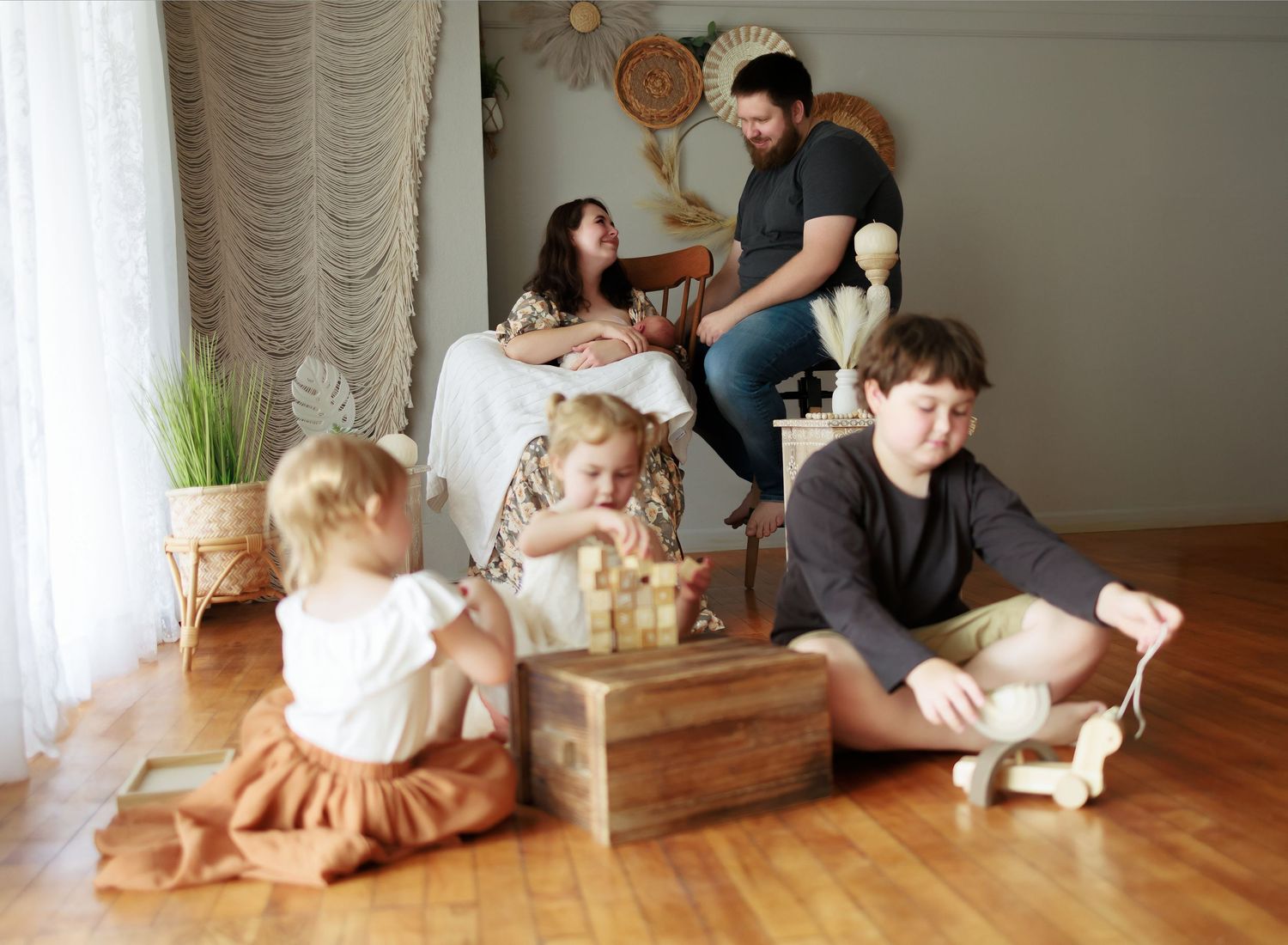 A photo of a family enjoying time with their newborn while their older children play