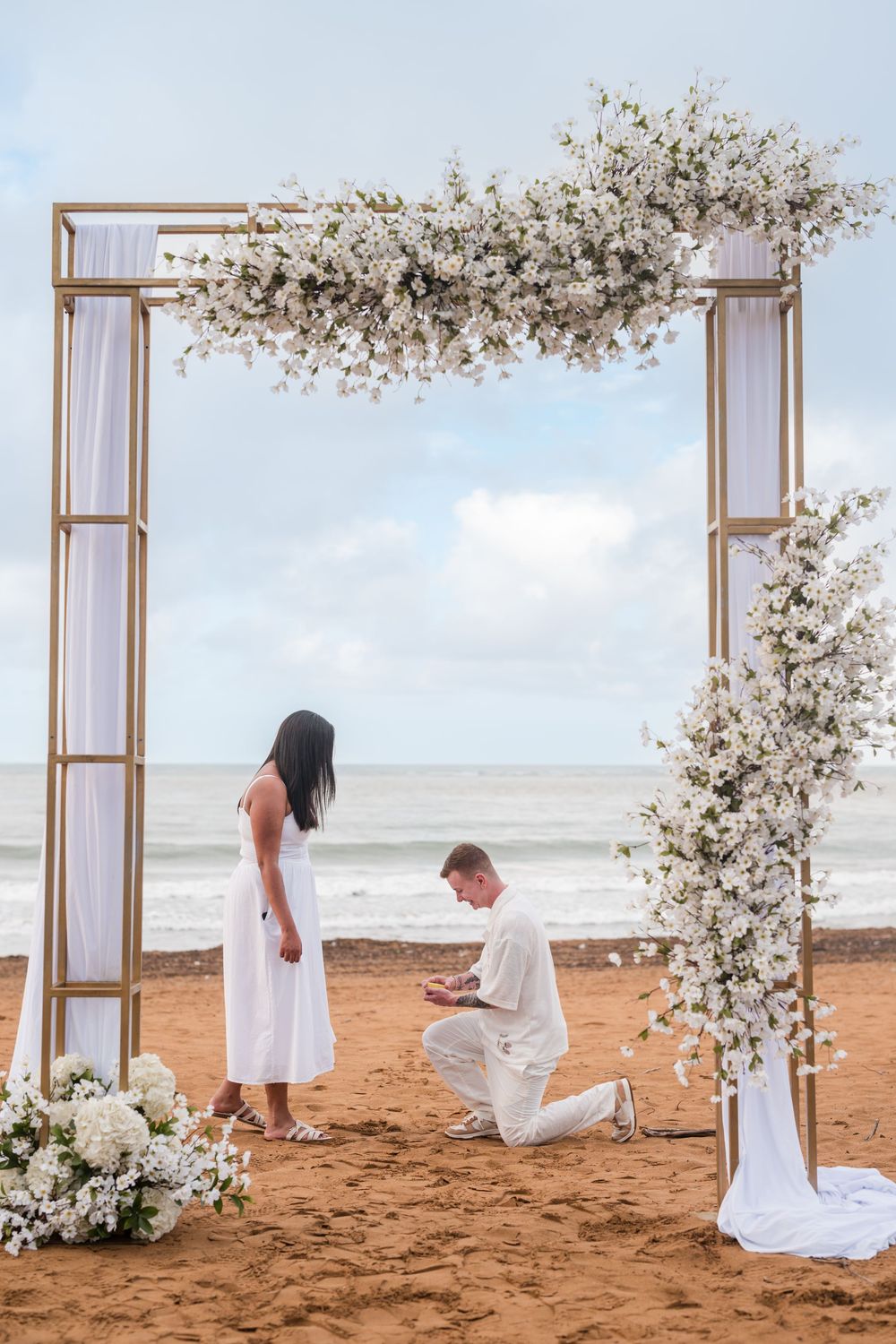 Couple standing under floral arch during engagement session at Wyndham Grand Rio Mar Puerto Rico