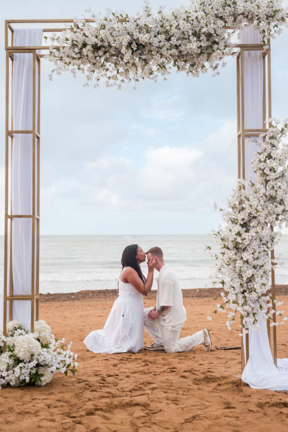 Couple sitting together under decorated arch during engagement photos at Wyndham Grand Rio Mar