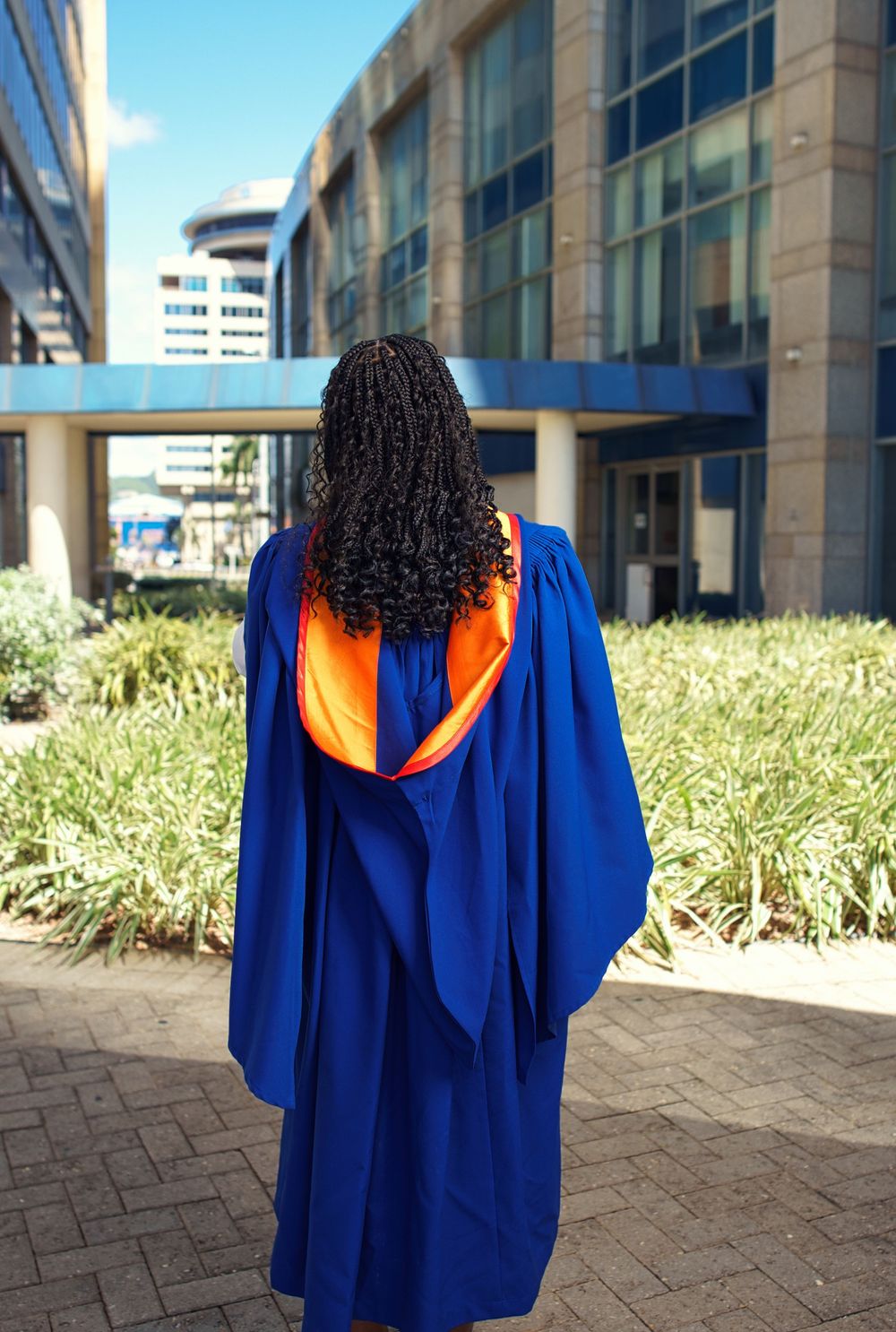 Series of photos showing graduate in royal blue graduation gown against architectural columns and landscaping.