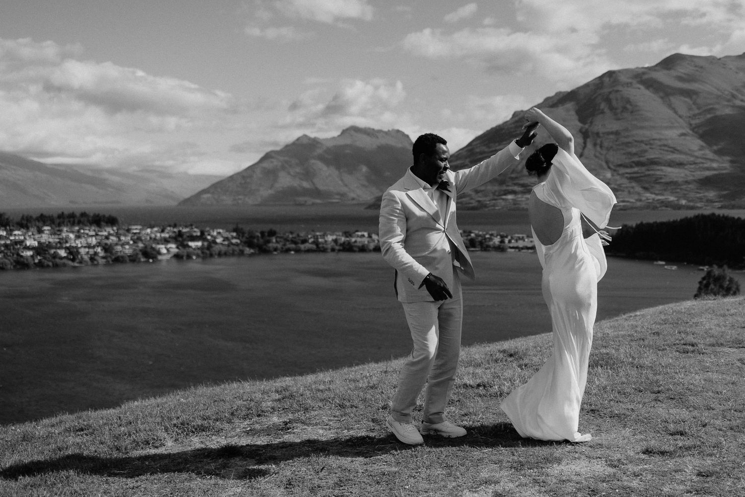 A black and white wedding photo captured on a hilltop overlooking Lake Wakatipu, Queenstown.
