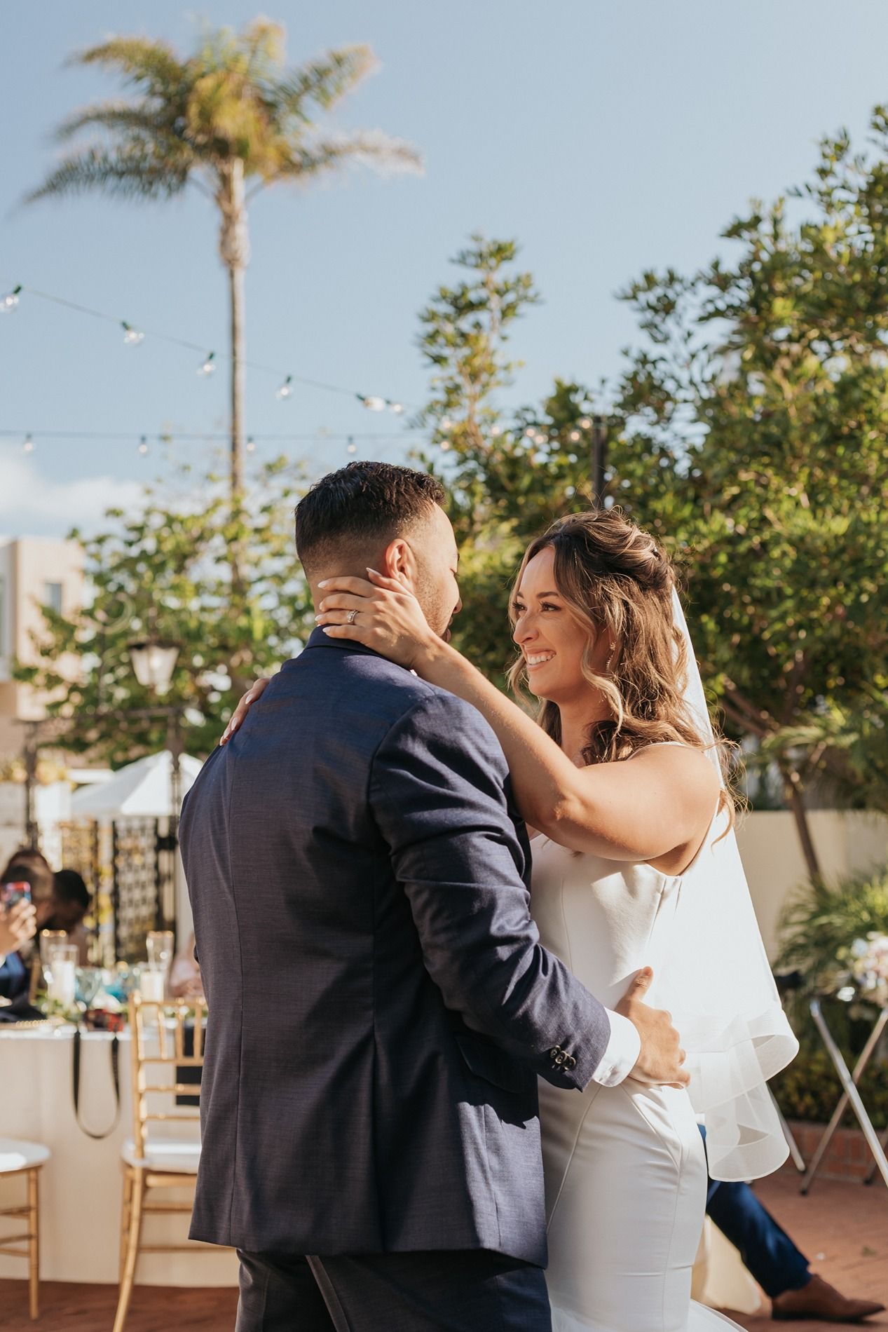Bride and groom share first dance outdoors at wedding reception with palm trees and string lights at Darlington House.