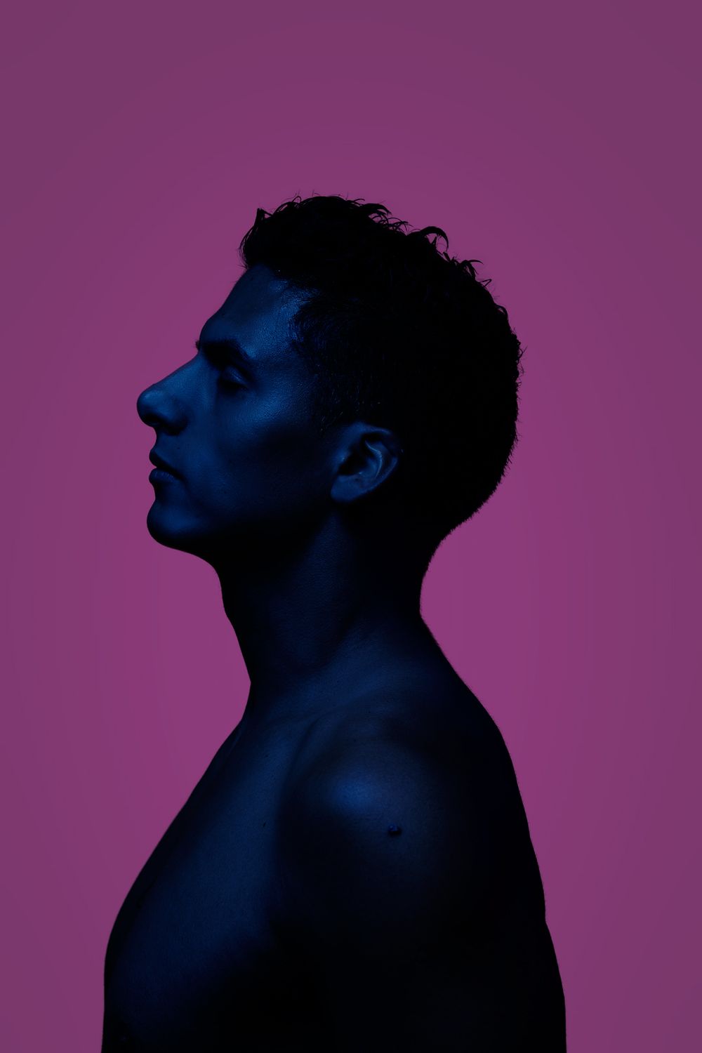 Artistic silhouette profile against purple background with dramatic blue lighting.