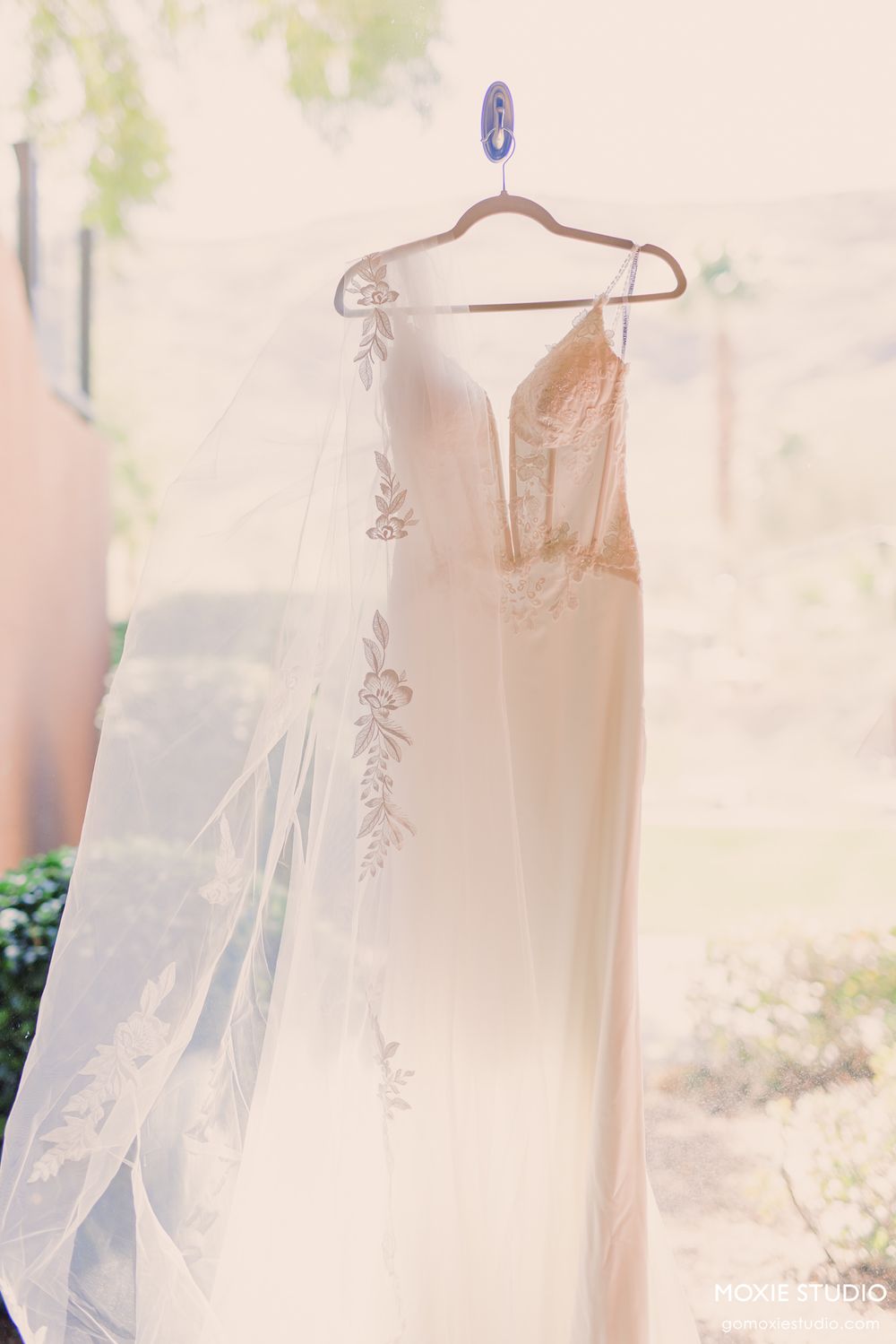Ethereal white lace wedding dresses hanging in a row with soft natural lighting creating a dreamy atmosphere.