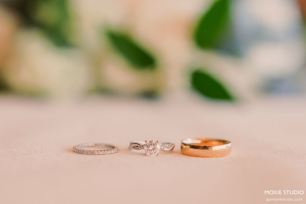 Close-up of elegant wedding rings with diamonds arranged on a light beige surface.