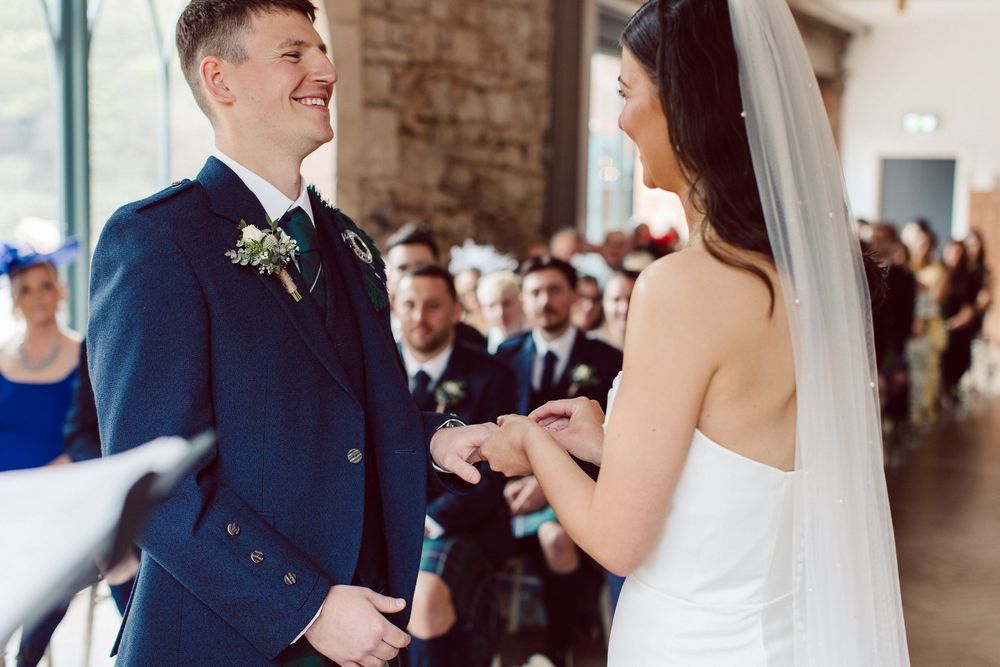 A bride and groom share their first dance at a wedding reception in a rustic brick-walled venue.