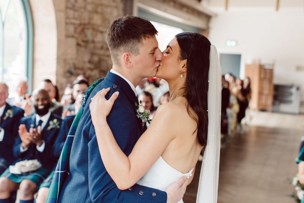 A couple shares romantic kisses in various locations including a stone archway and outdoor settings.