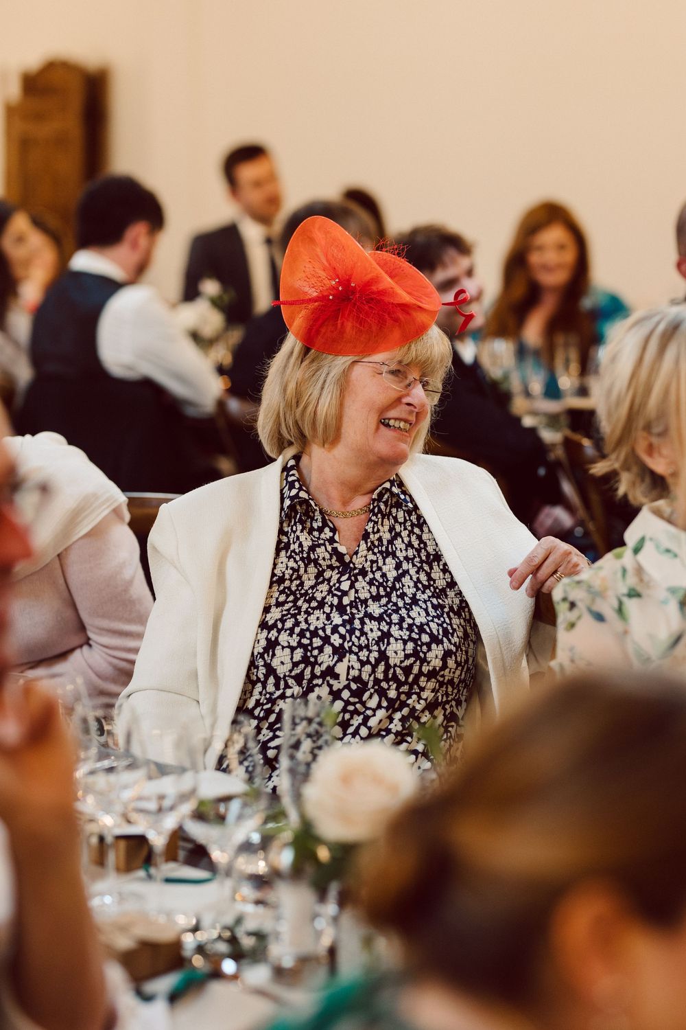 Wedding guests enjoying a lively reception dinner at tables decorated with elegant centerpieces.