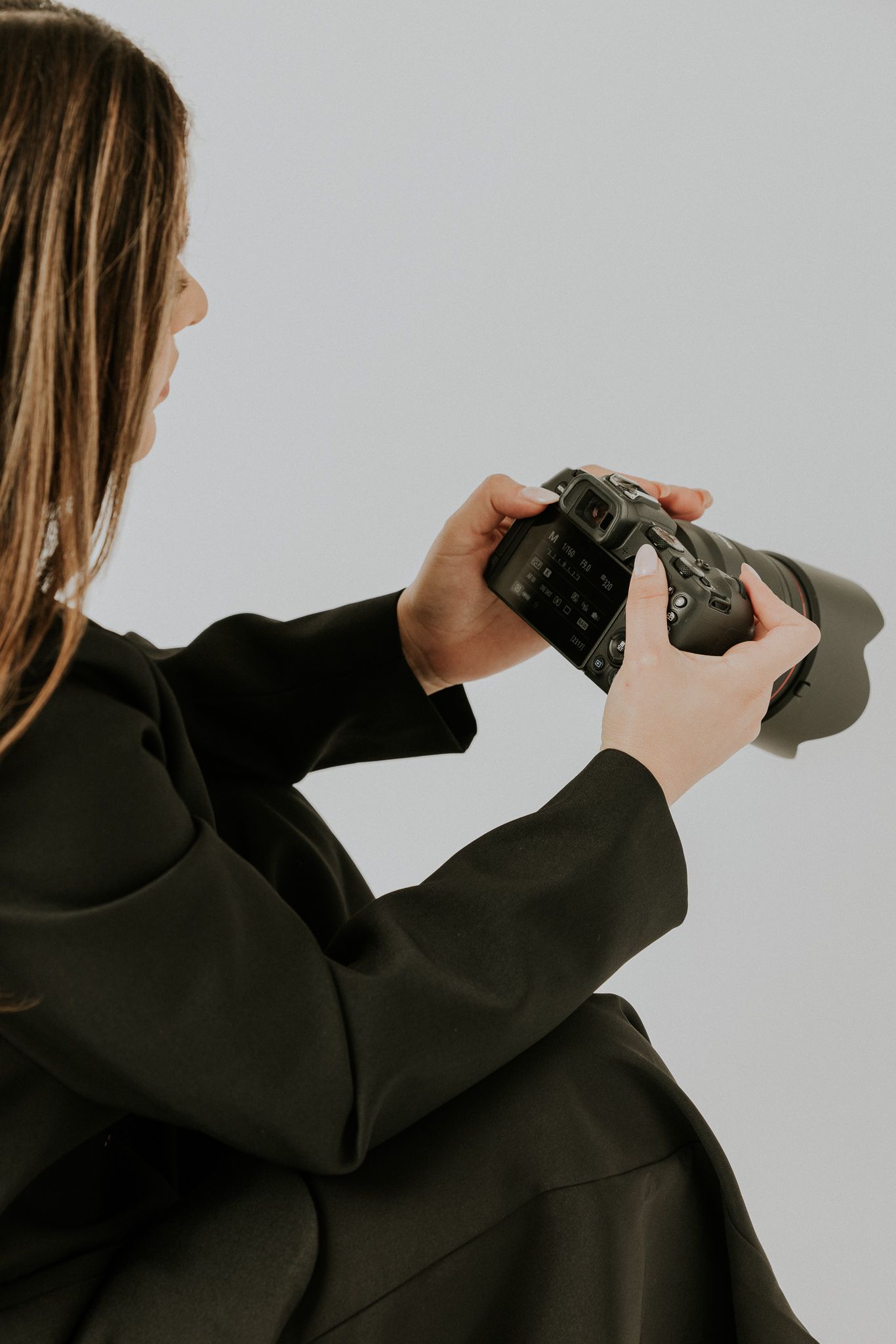 A sequence of hands holding a black camera shown from different angles against a light background.