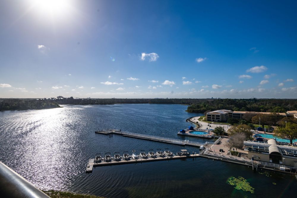Aerial panoramic view of a coastal marina with boats and docks stretching along the blue waterfront.