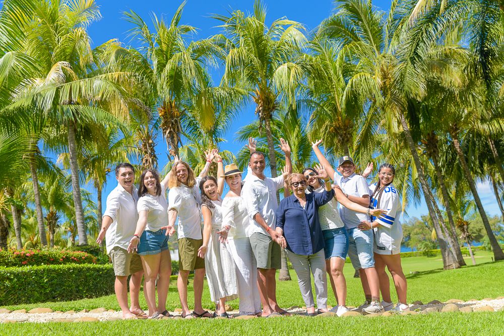 A group celebrates together on a sunny day surrounded by tropical palm trees in a lush garden setting.