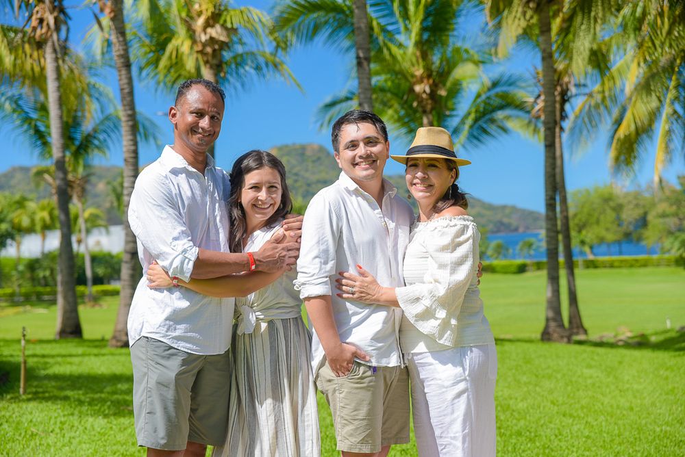 A small group stands together on a grassy lawn with tall palm trees and blue skies in Hawaii.