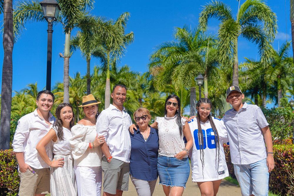 A casual group photo taken outdoors with palm trees and tropical landscaping at a resort.