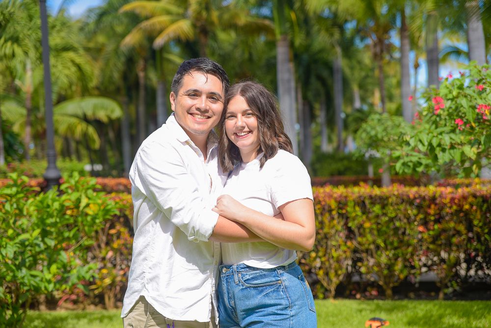 Couple sharing an intimate embrace in a scenic tropical garden setting with palm trees and greenery.