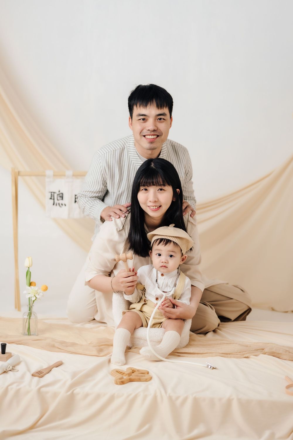 抓周寫真、全家福，渴望影像紀錄一歲寶寶抓周儀式與親子互動，透過自然光棚拍呈現溫暖氛圍，畫面包含寶寶拿取抓周物品、爬行探索與父母陪伴互動，整體風格乾淨柔和、色調溫潤，適合尋找屏東抓周寫真、全家福攝影、寶寶周歲紀念攝影的家庭參考，依照服裝而改變佈景，呈現真實自然且具故事感的家庭影像。