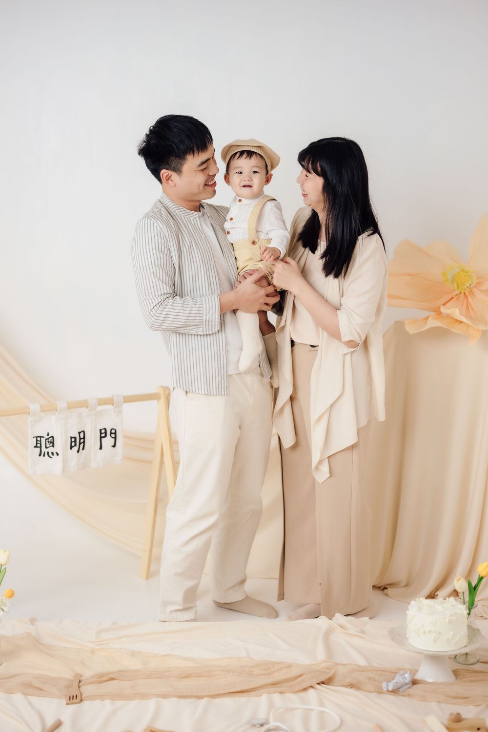 抓周寫真、全家福，渴望影像紀錄一歲寶寶抓周儀式與親子互動，透過自然光棚拍呈現溫暖氛圍，畫面包含寶寶拿取抓周物品、爬行探索與父母陪伴互動，整體風格乾淨柔和、色調溫潤，適合尋找屏東抓周寫真、全家福攝影、寶寶周歲紀念攝影的家庭參考，依照服裝而改變佈景，呈現真實自然且具故事感的家庭影像。
