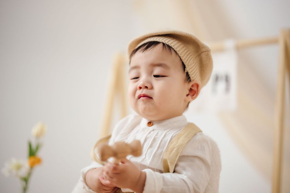 抓周寫真、全家福，渴望影像紀錄一歲寶寶抓周儀式與親子互動，透過自然光棚拍呈現溫暖氛圍，畫面包含寶寶拿取抓周物品、爬行探索與父母陪伴互動，整體風格乾淨柔和、色調溫潤，適合尋找屏東抓周寫真、全家福攝影、寶寶周歲紀念攝影的家庭參考，依照服裝而改變佈景，呈現真實自然且具故事感的家庭影像。