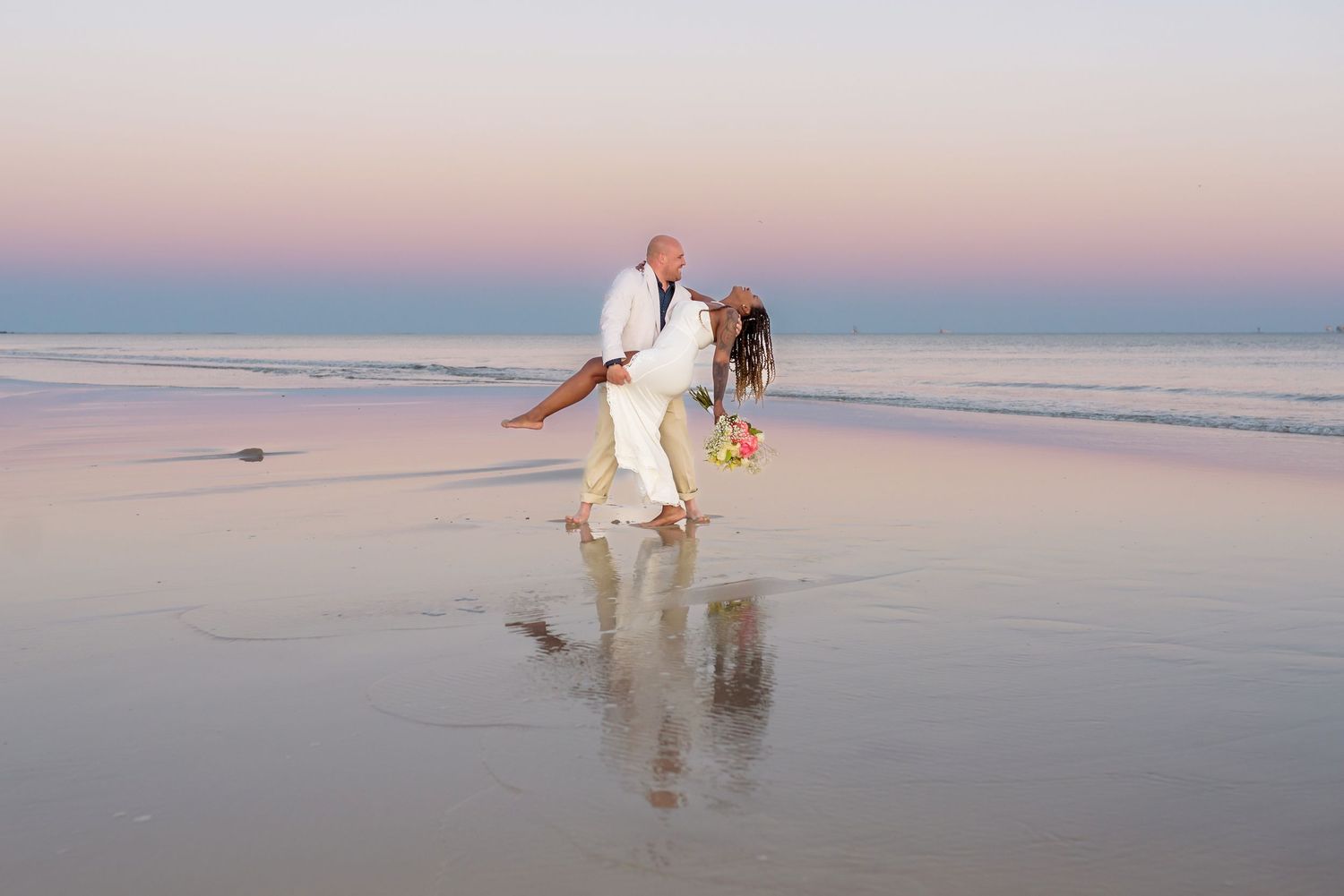 Wedding couple sharing a romantic sunset moment on Dauphin Island with reflections on the shoreline and soft coastal light.