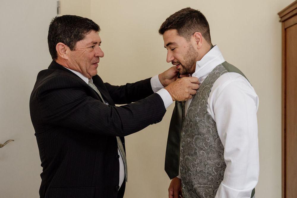 Two men in formal attire are engaged in a friendly interaction, appearing to have a conversation.