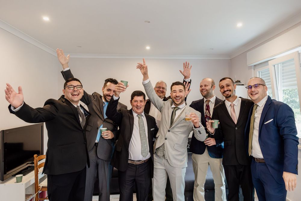 A group of men in formal attire celebrating and posing together in an indoor setting.
