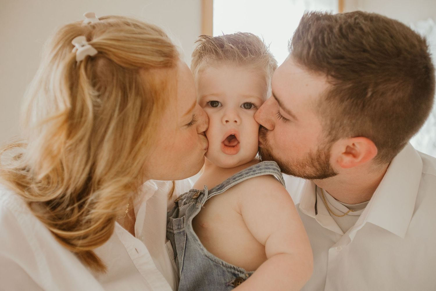 A tender family moment captured as parents kiss their baby's cheeks.