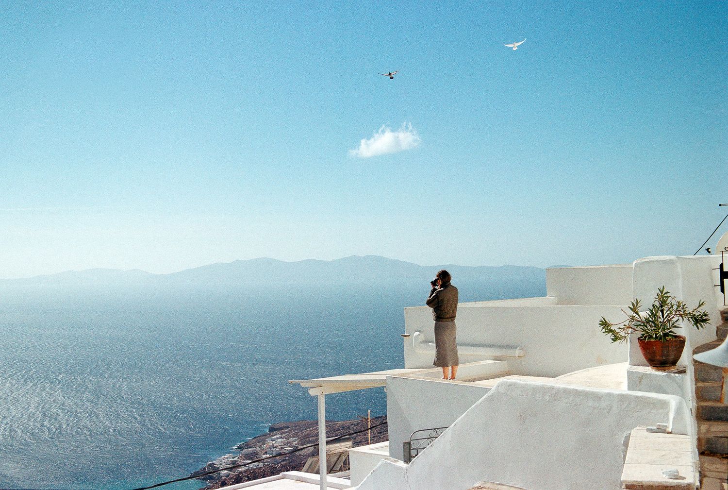 Woman standing barefoot by the sea, captured in a candid summer moment.