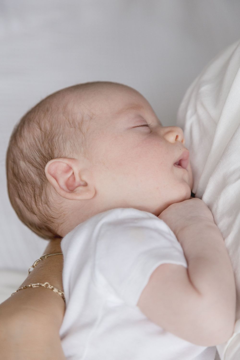 "Newborn baby sleeping peacefully in mother's arms during elegant Washington DC lifestyle newborn session."