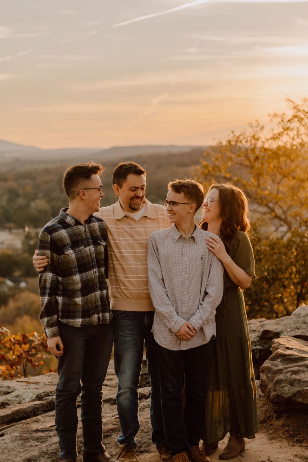 Sunset family portrait on mountain overlook with warm golden lighting.