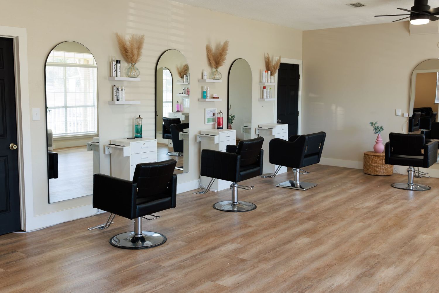 Interior view of modern hair salon with black styling chairs and hardwood floors.
