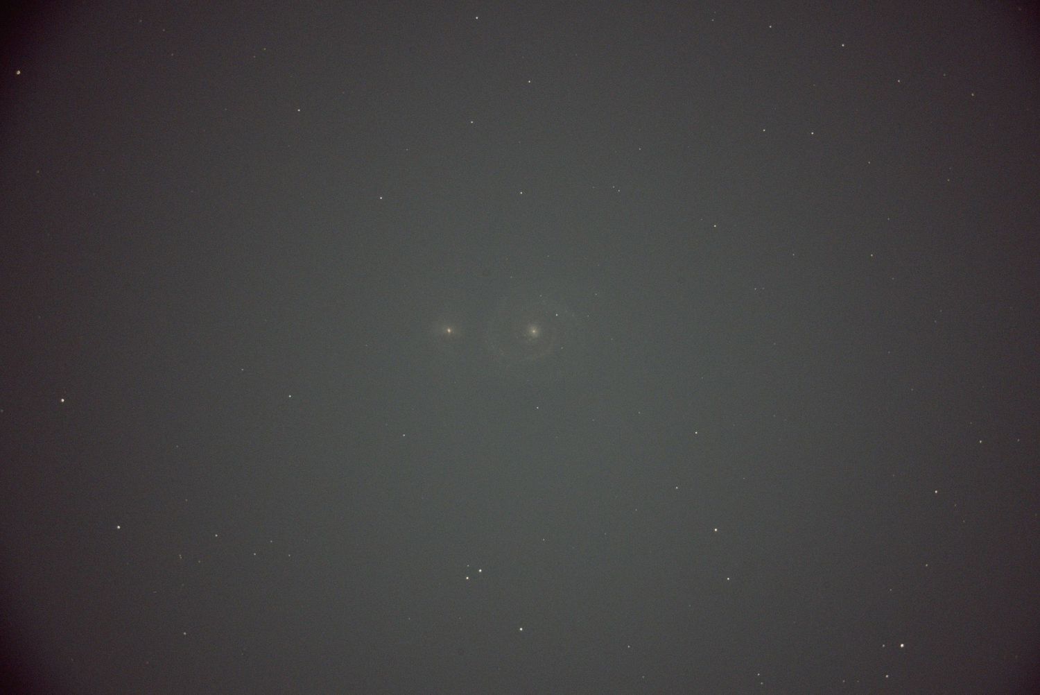 A blurry dark gray photograph with faint dots of light scattered against a hazy background.